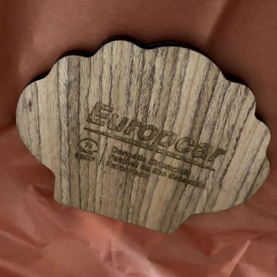Foto real de la concha de madera de nogal con el logotipo de Europcar y del Festival de San Sebastián grabado a láser, sobre papel de seda